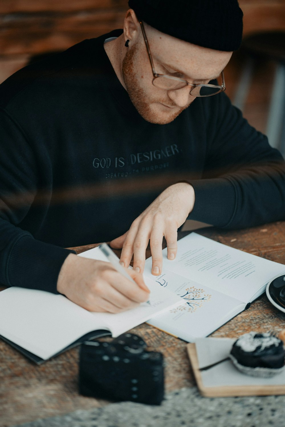 a man sitting at a table with a book and pen