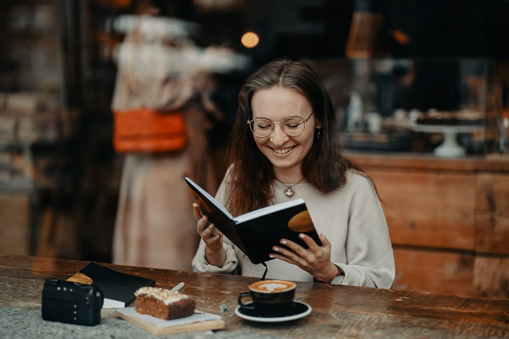 a woman sitting at a table reading a book