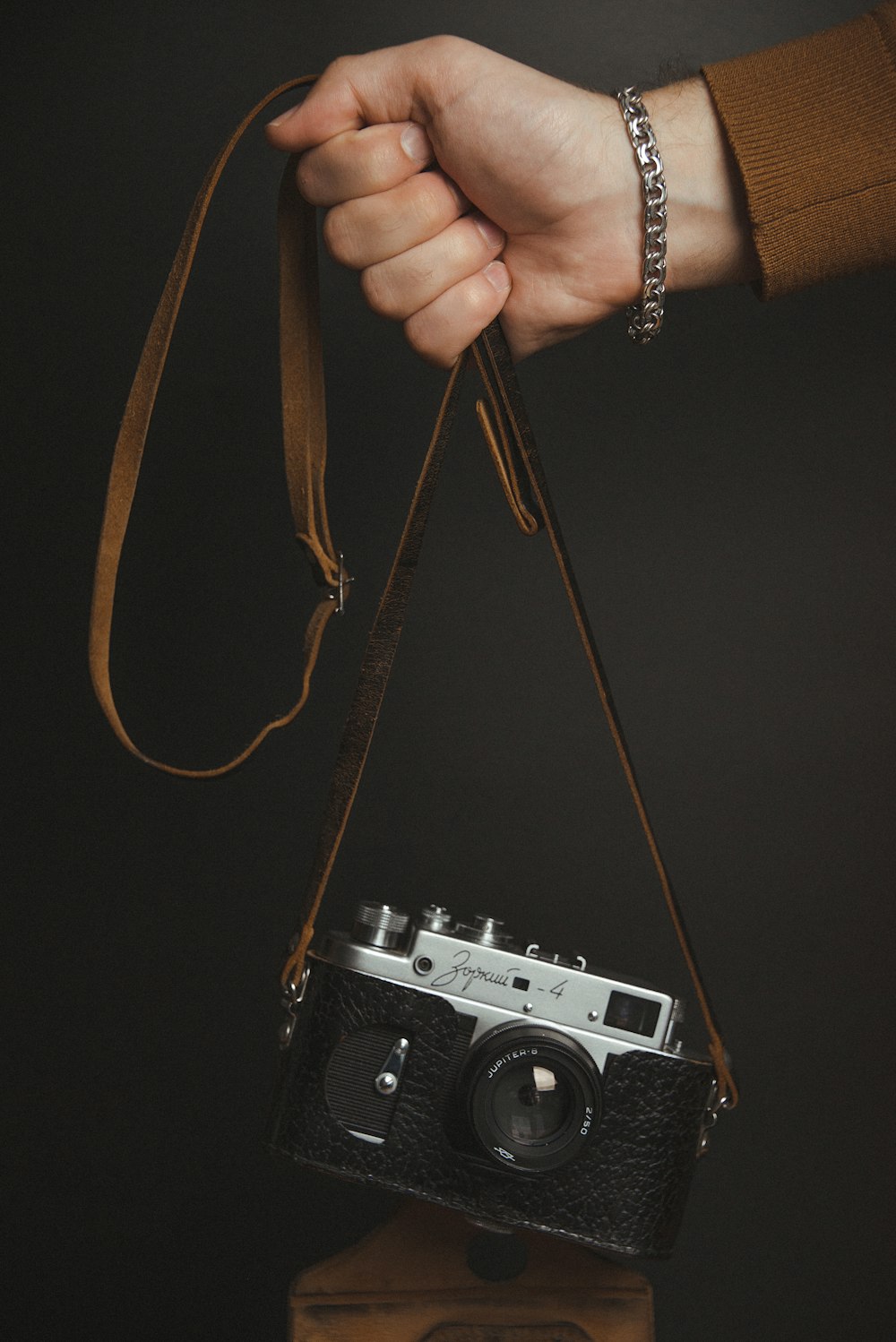 a person's hand holding a camera on top of a wooden block