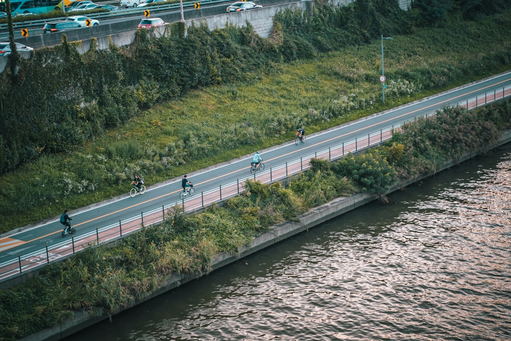 um grupo de pessoas andando de bicicleta por uma estrada ao lado de um rio