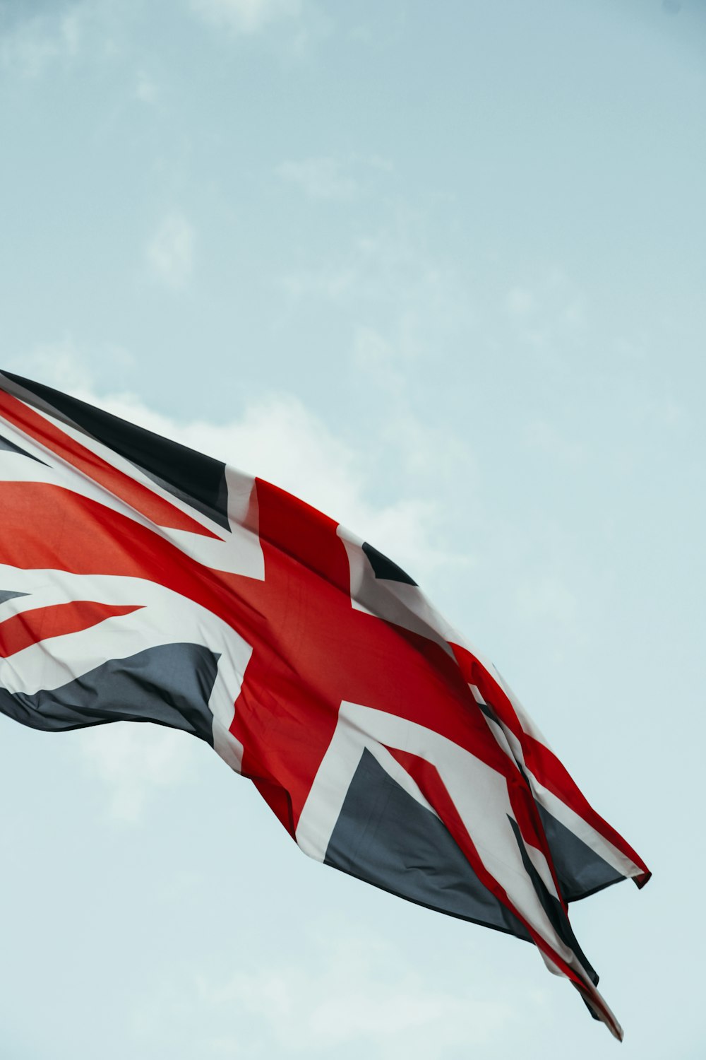 a flag flying in the wind with a blue sky in the background