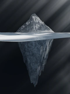 A close-up of an iceberg with a golden pen nib glowing beneath the waterline, symbolizing hidden ideas.