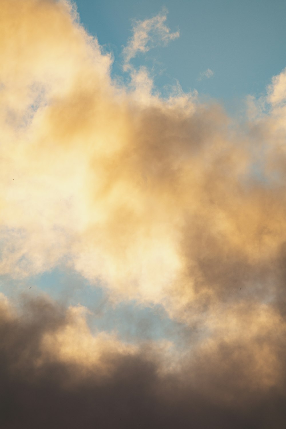 a plane flying through a cloudy blue sky