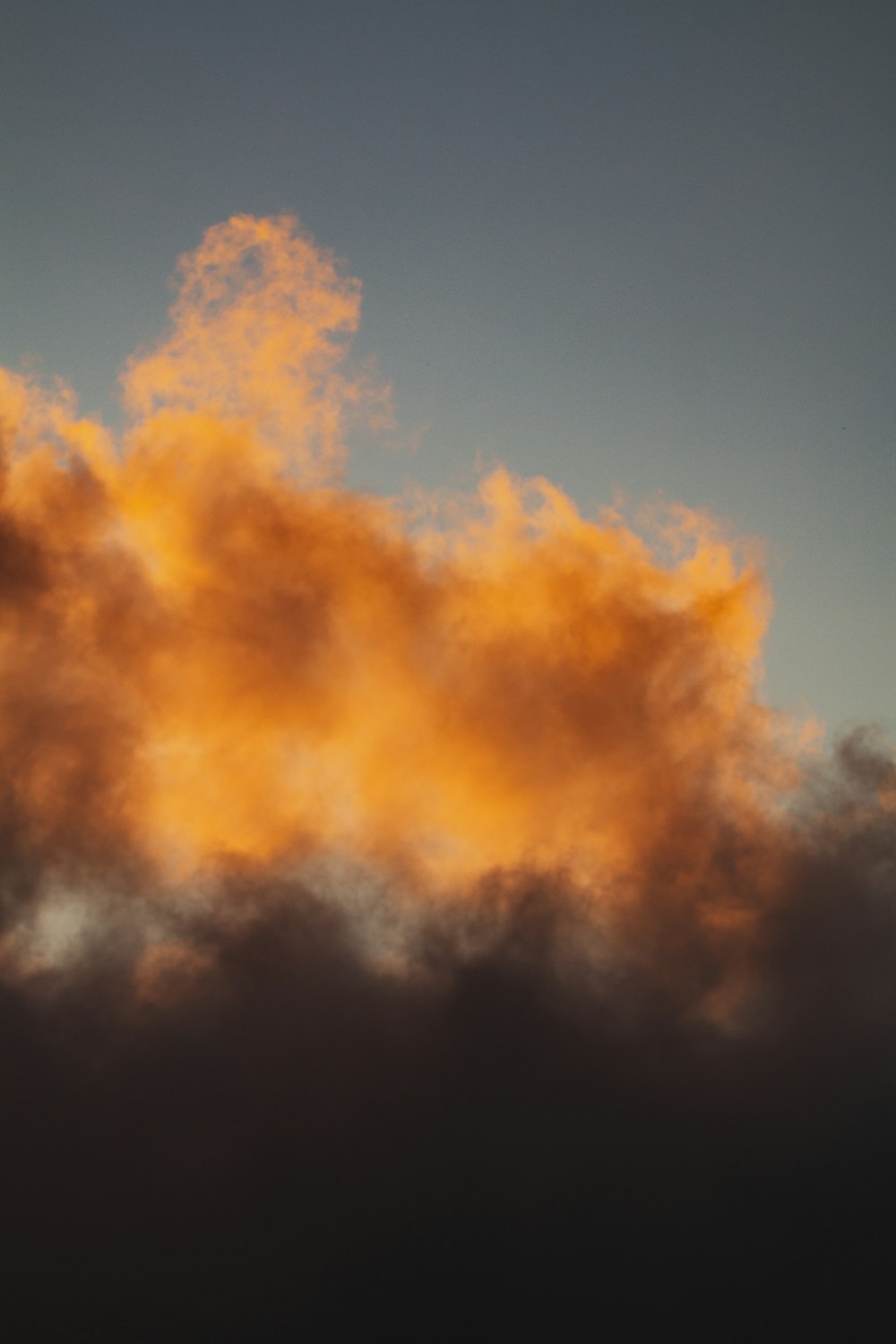 a plane flying through a cloudy sky at sunset