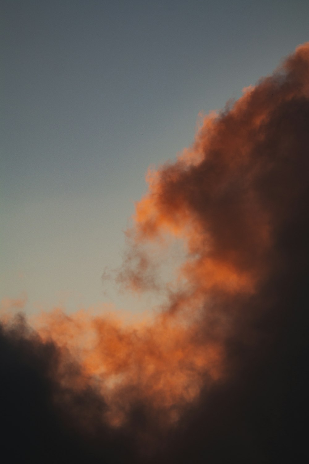 a plane flying through a cloudy sky at sunset