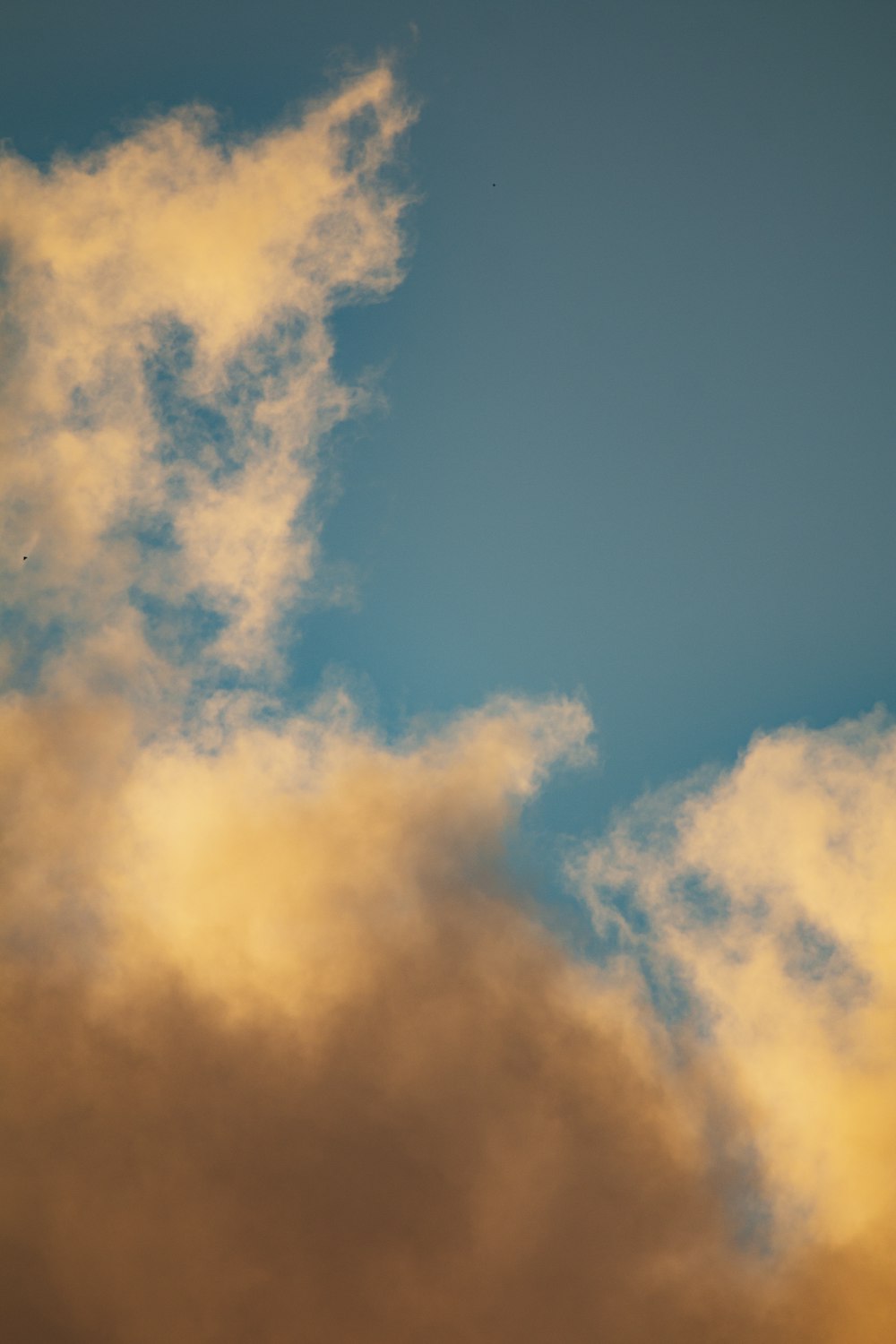 a plane flying through a cloudy blue sky