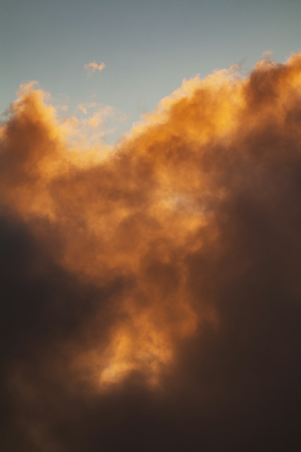 a plane flying through a cloudy sky at sunset