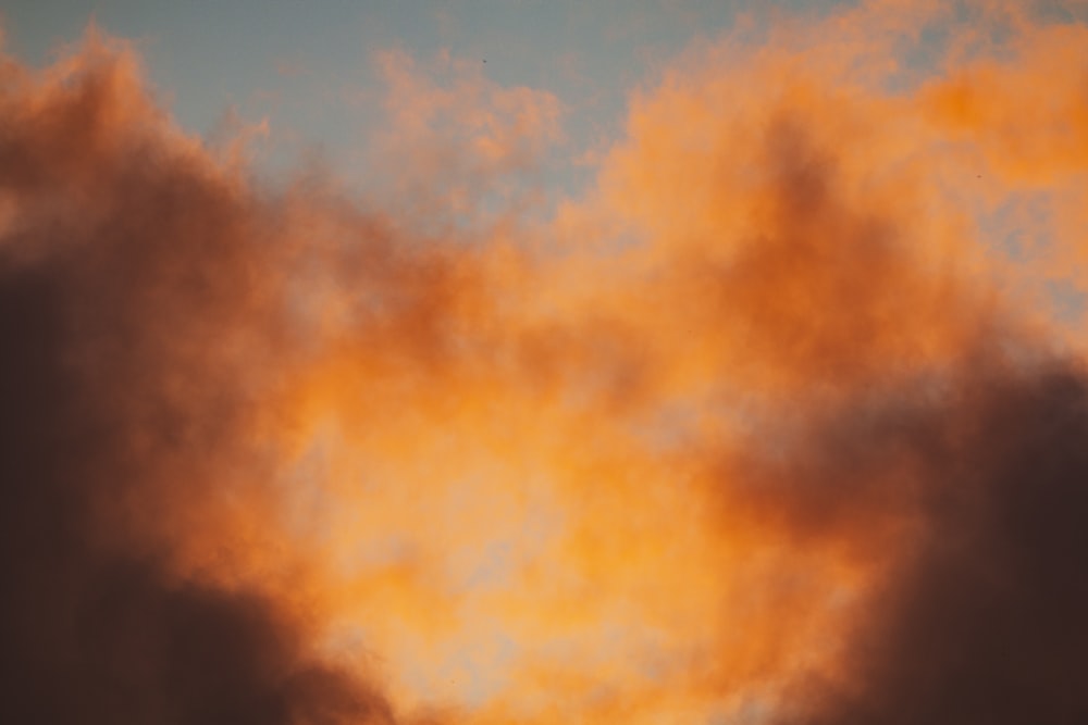 a plane flying through a cloudy sky at sunset