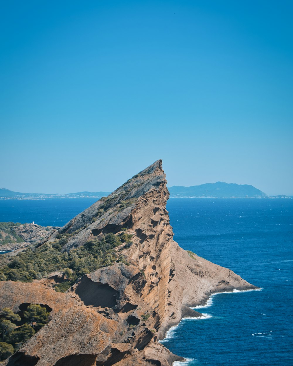 a rocky cliff with a body of water in the background