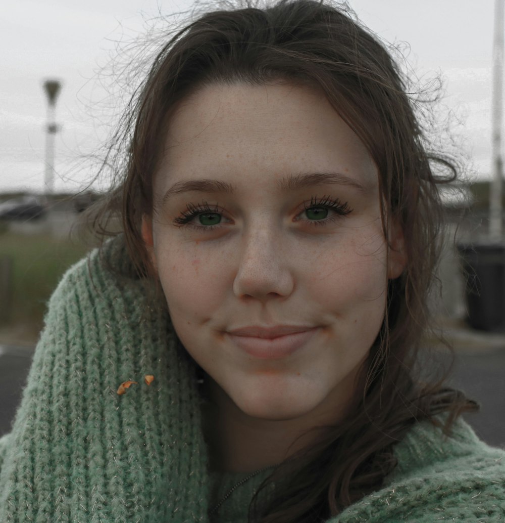 a woman with a green sweater and a cell phone