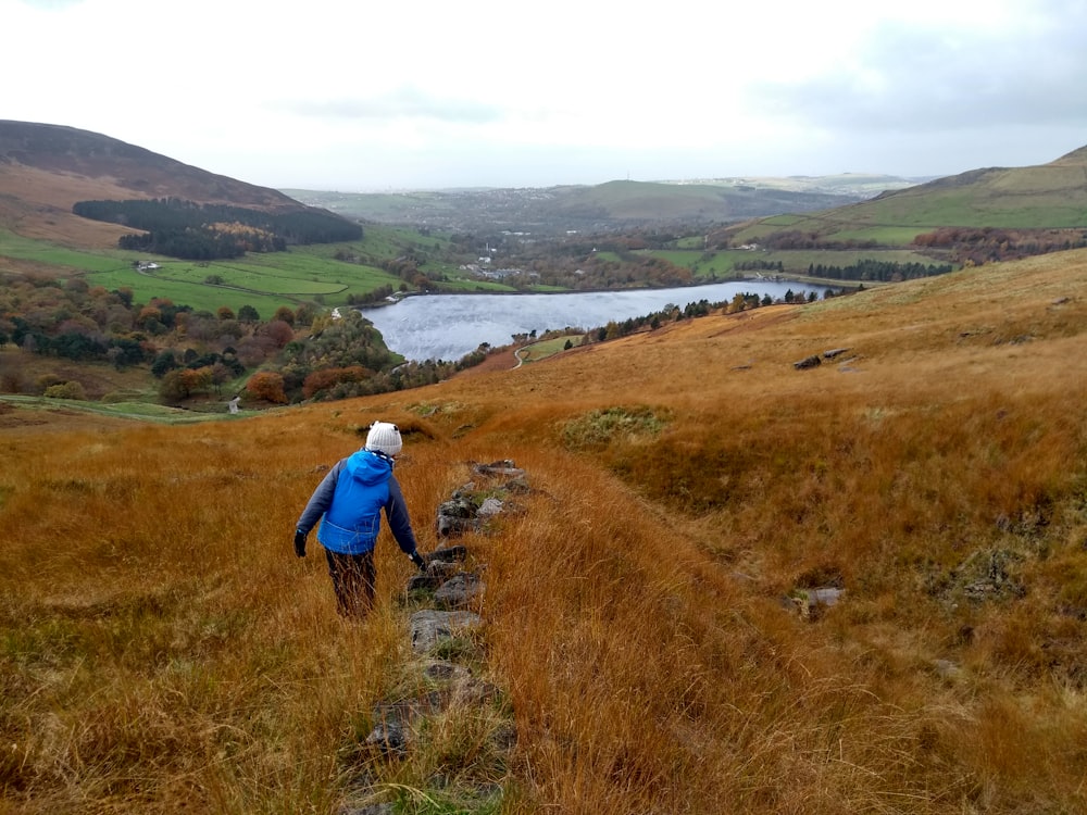 a person in a blue jacket walking up a hill