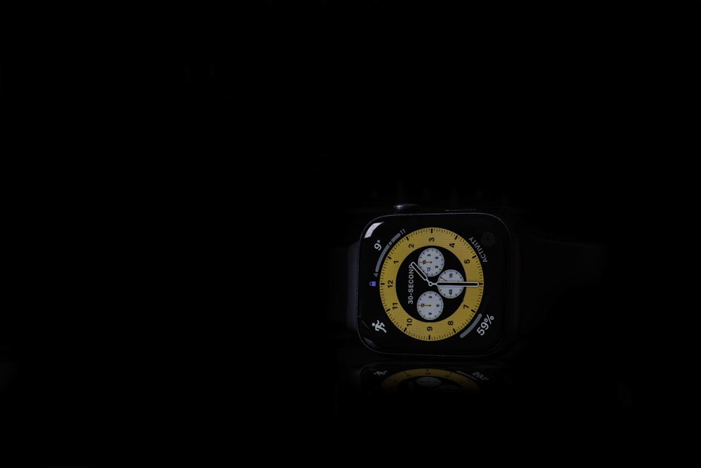 a watch with a yellow face in the dark