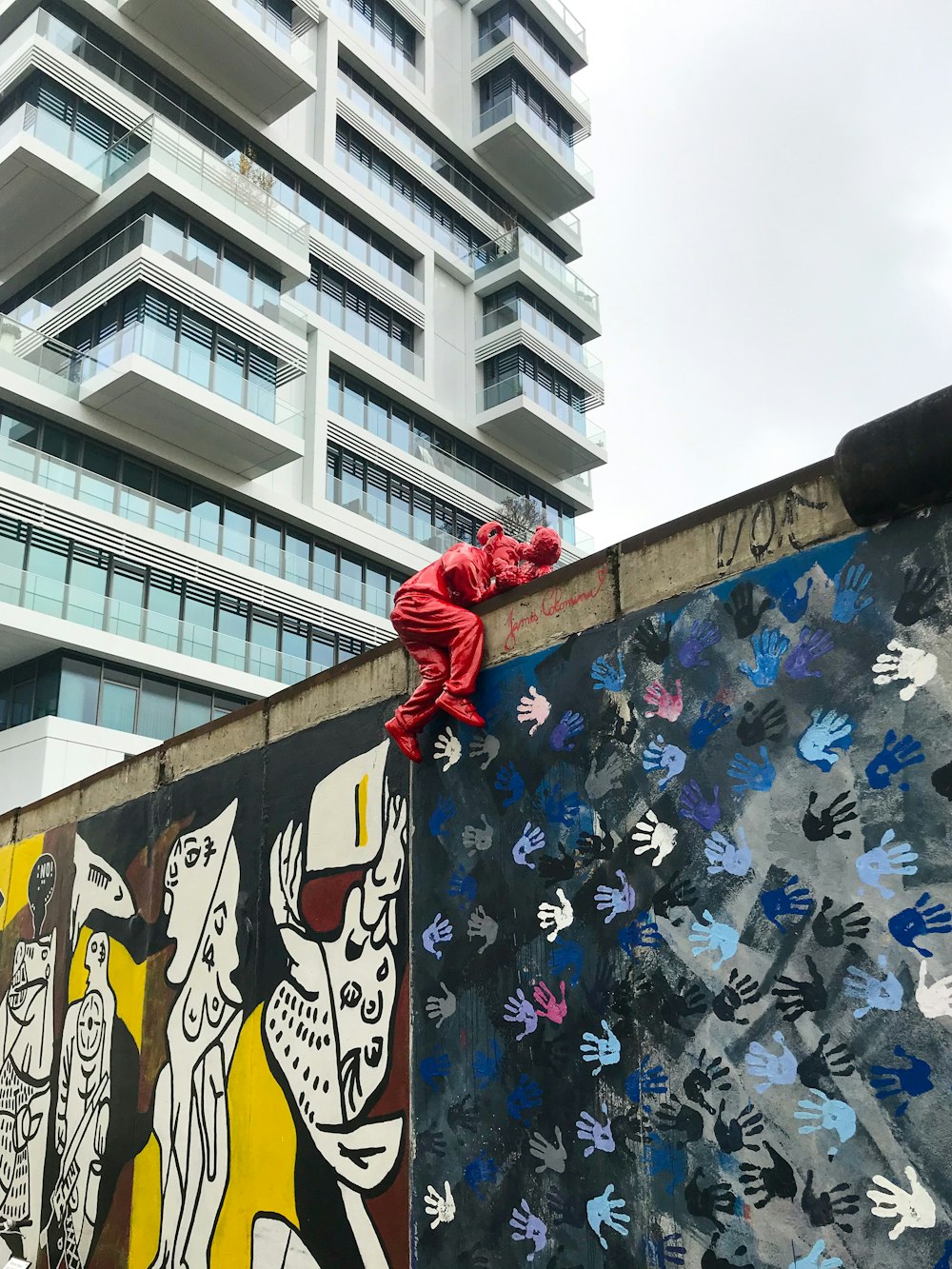 a wall covered in graffiti with a building in the background