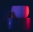 A coffee cup and a Nespresso coffee pod illuminated by red and blue lights with a portion of the Nespresso logo visible below them. The image has a moody and atmospheric feel, with a focus on contrasting colors and minimalistic design.