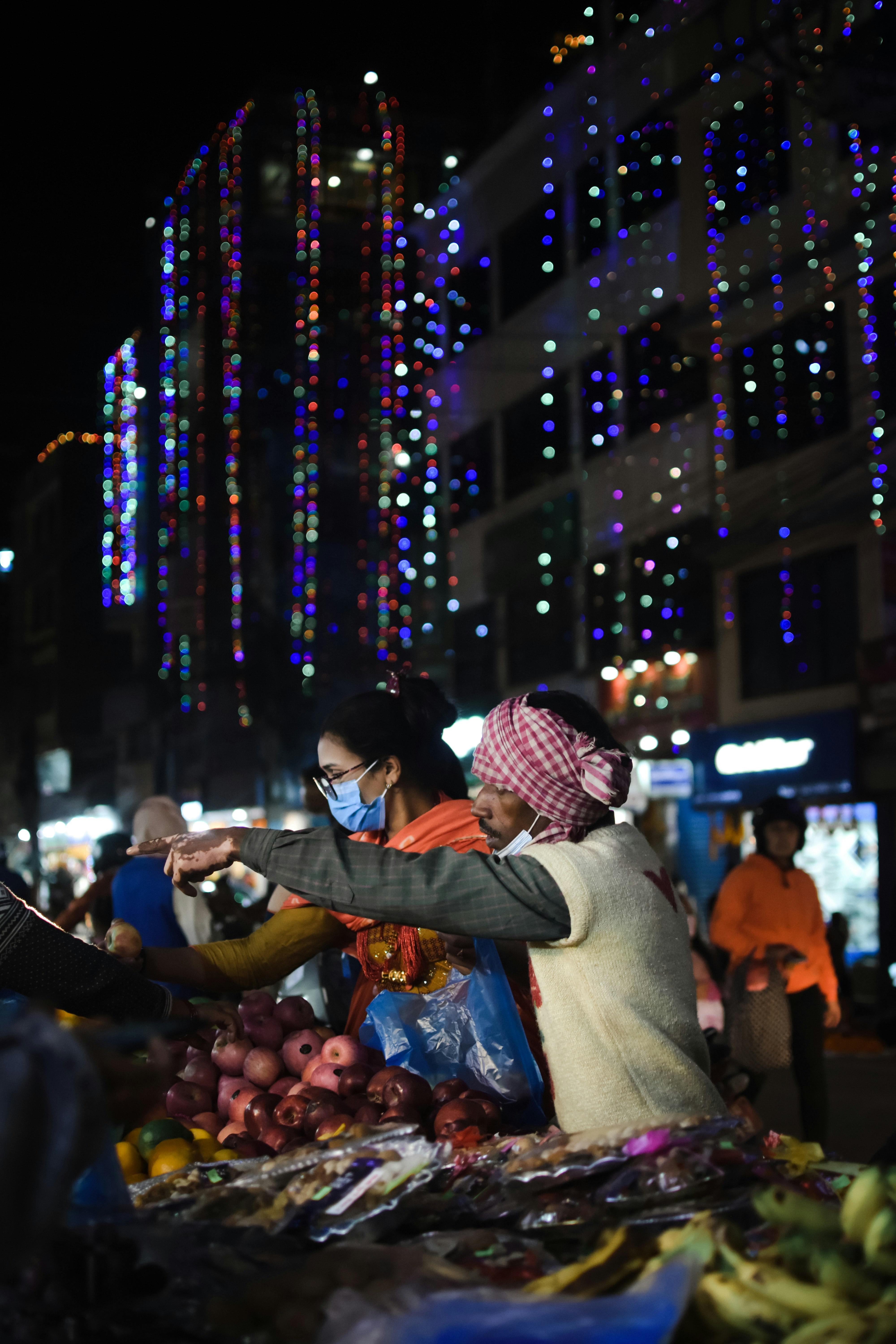 果物の山の隣に立っている女性のカップル