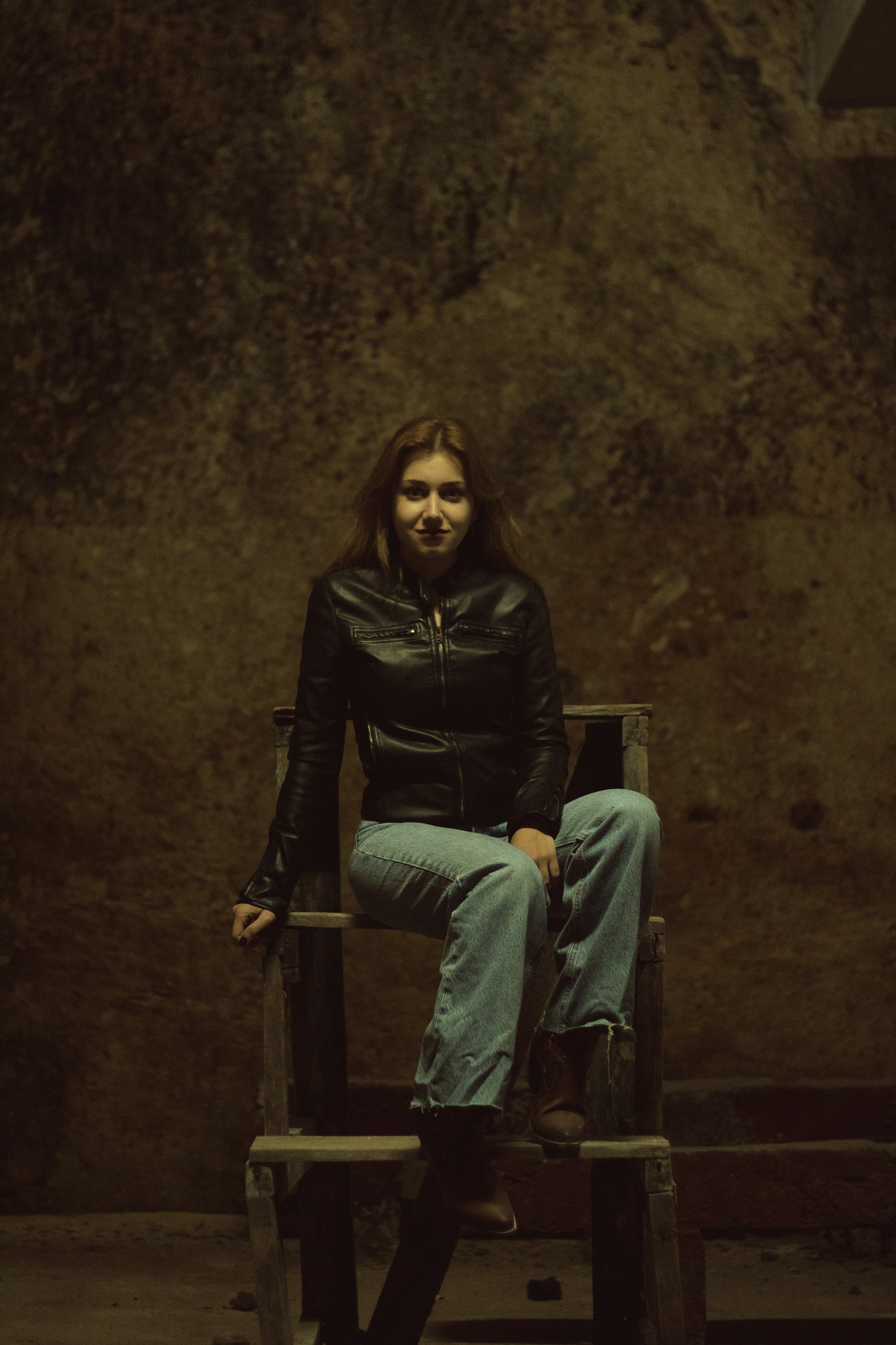 a woman is sitting on a wooden chair