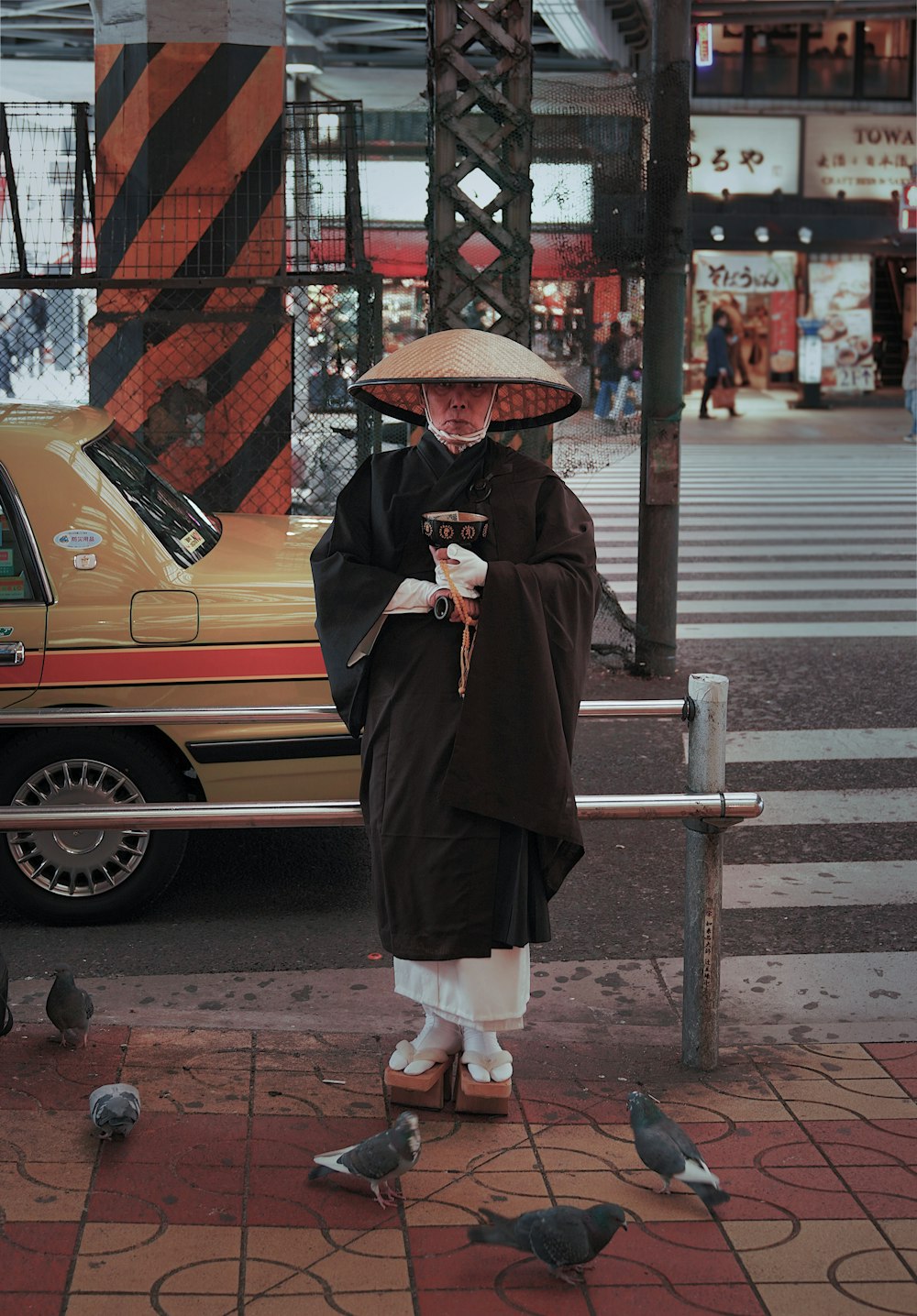 a woman standing on a street corner with pigeons around her