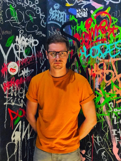 a man standing in front of a wall covered in graffiti