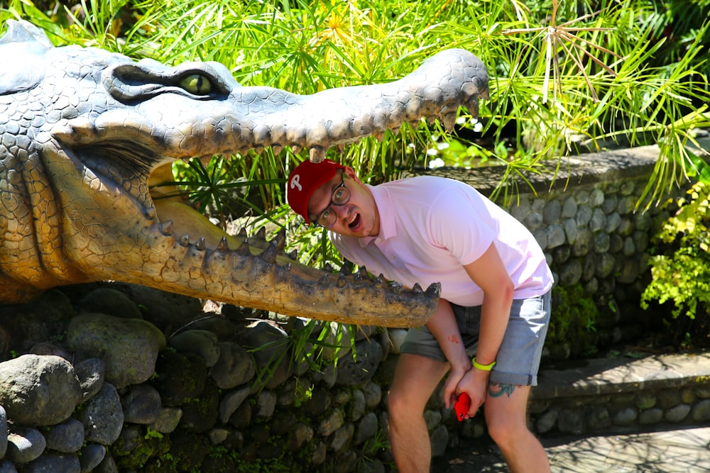 a man standing next to a statue of a crocodile