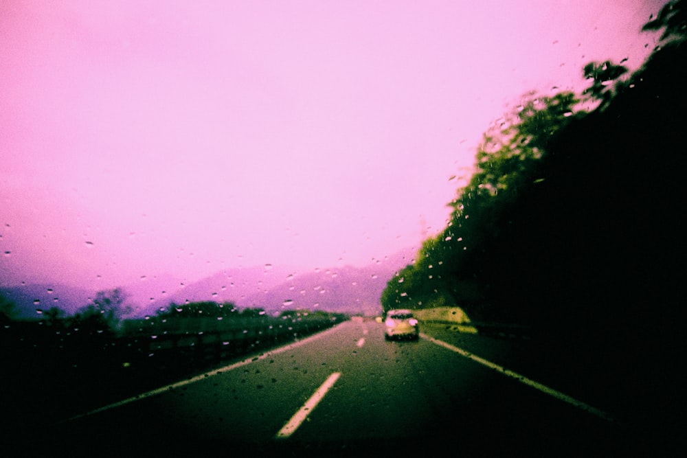 a car driving down a road next to a lush green forest