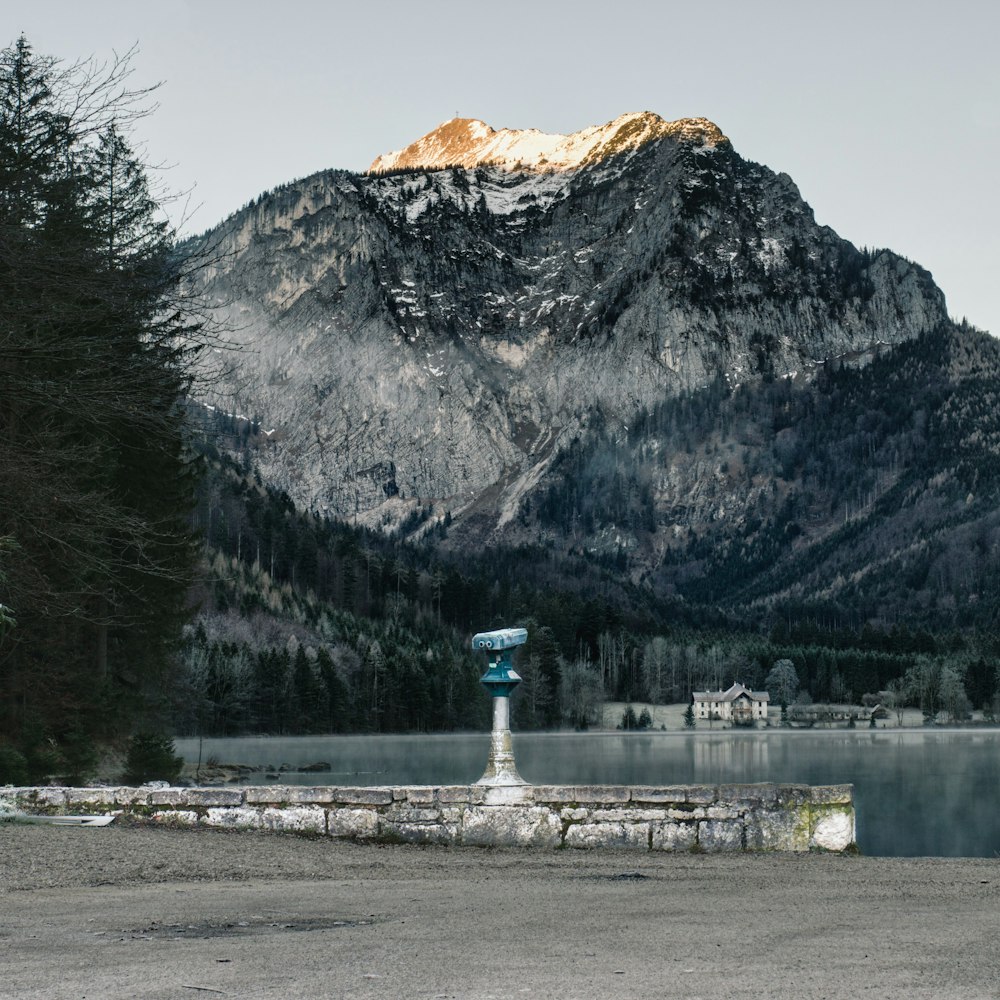 uma estátua em frente a um lago com montanhas no fundo