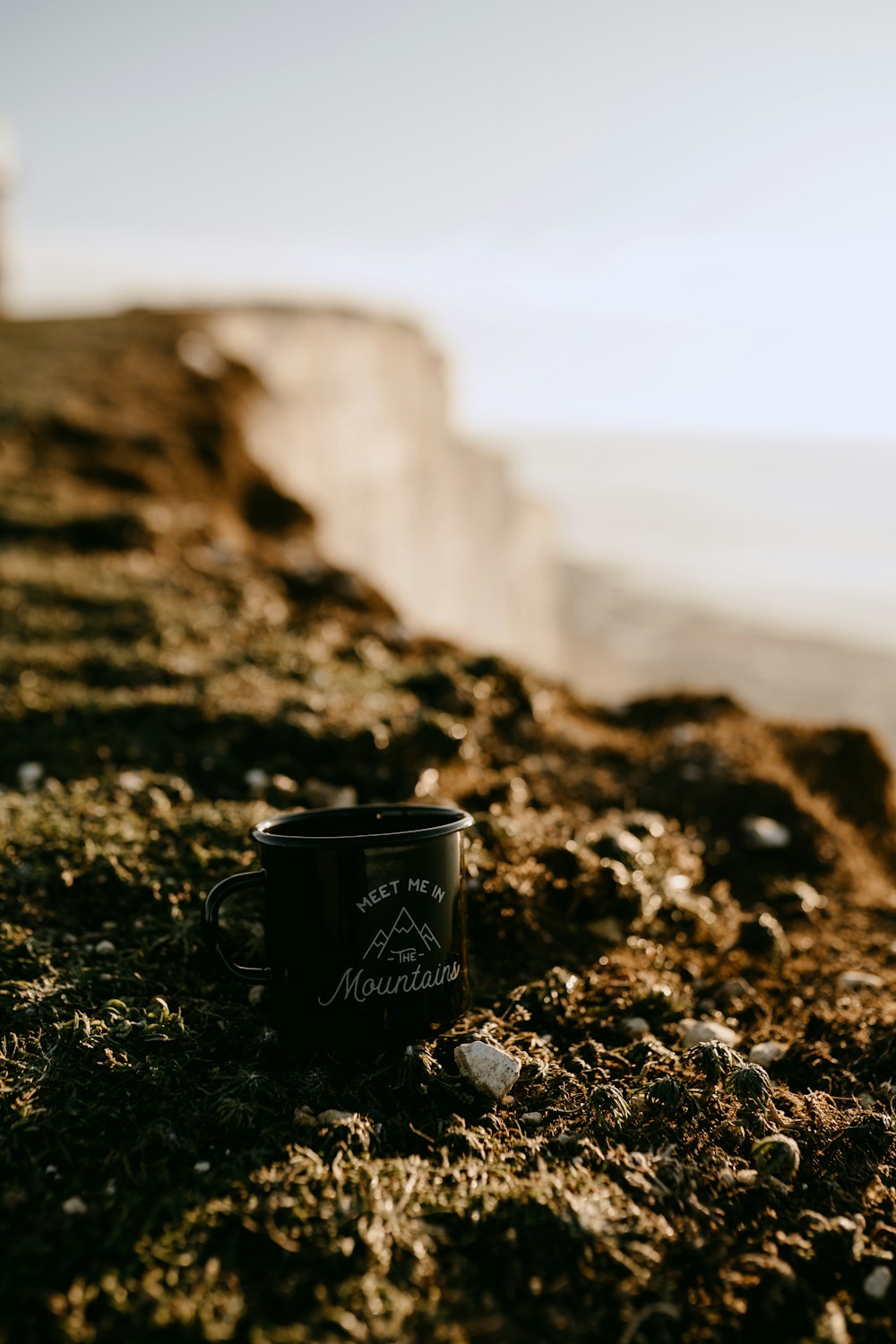 a cup of coffee sitting on the side of a cliff