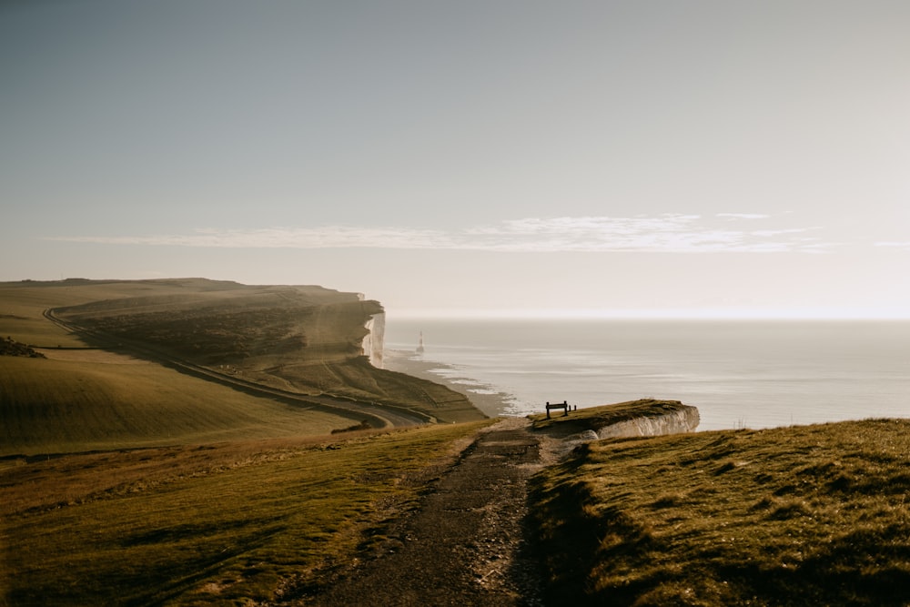 uma pessoa sentada em um banco em uma colina com vista para o oceano