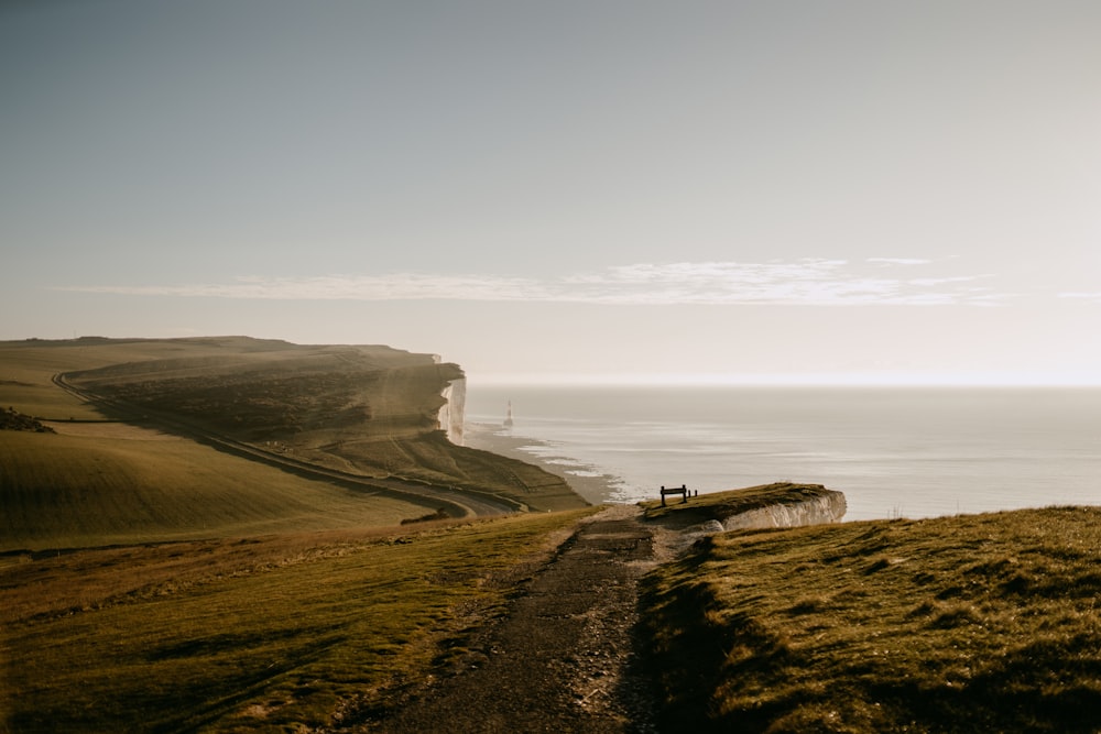 a person sitting on a bench on a hill overlooking the ocean