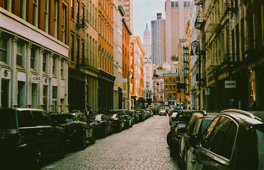 a street lined with parked cars and tall buildings