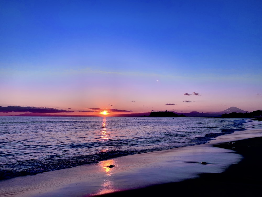 o sol está se pondo sobre a água na praia