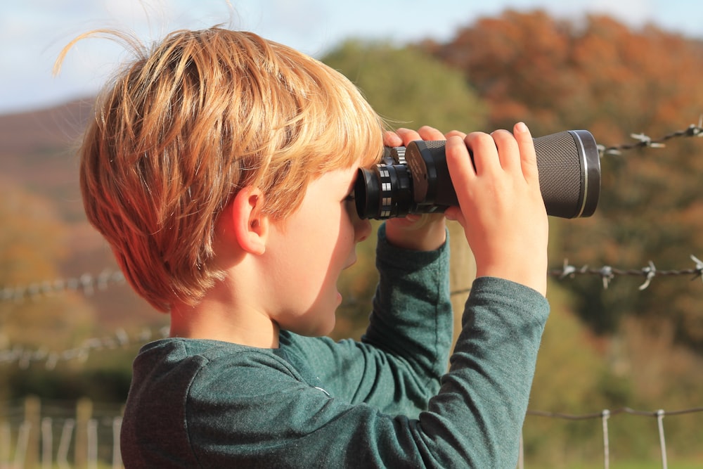 a young boy looking through a pair of binoculars