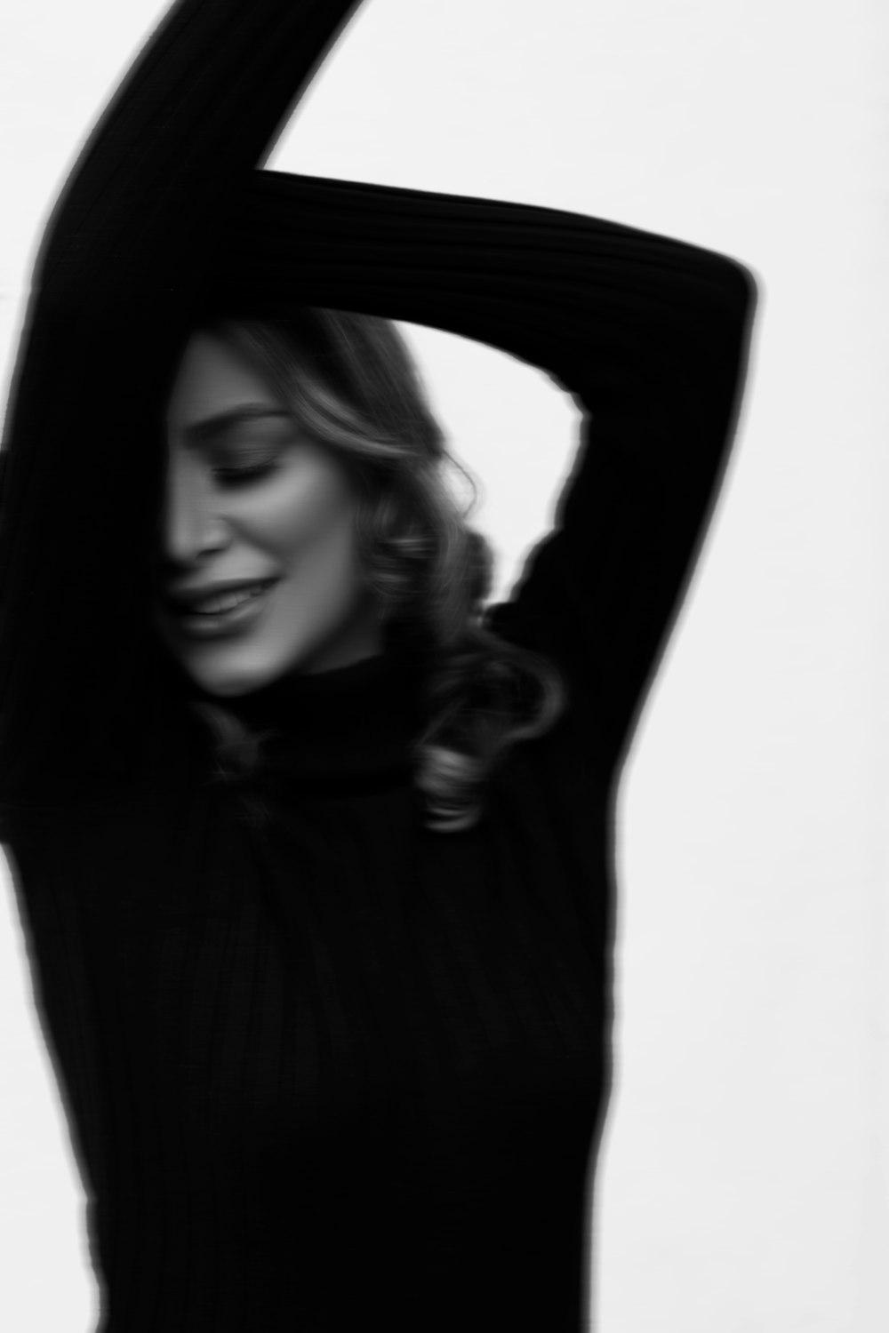 a woman in a black sweater is holding her arms behind her head
