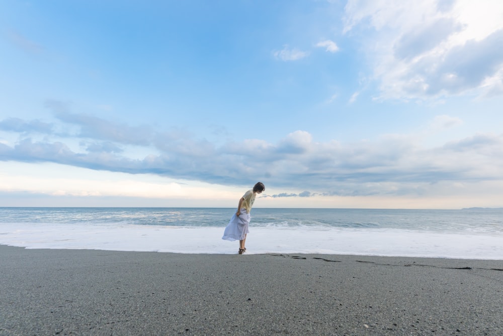 a woman in a white dress standing on a beach