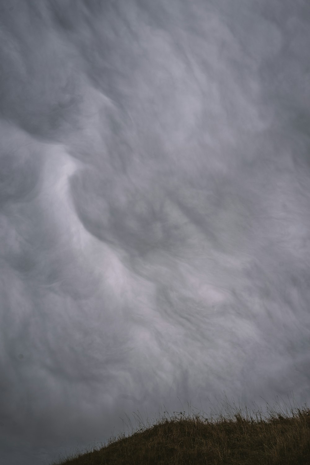 a person standing on top of a hill under a cloudy sky