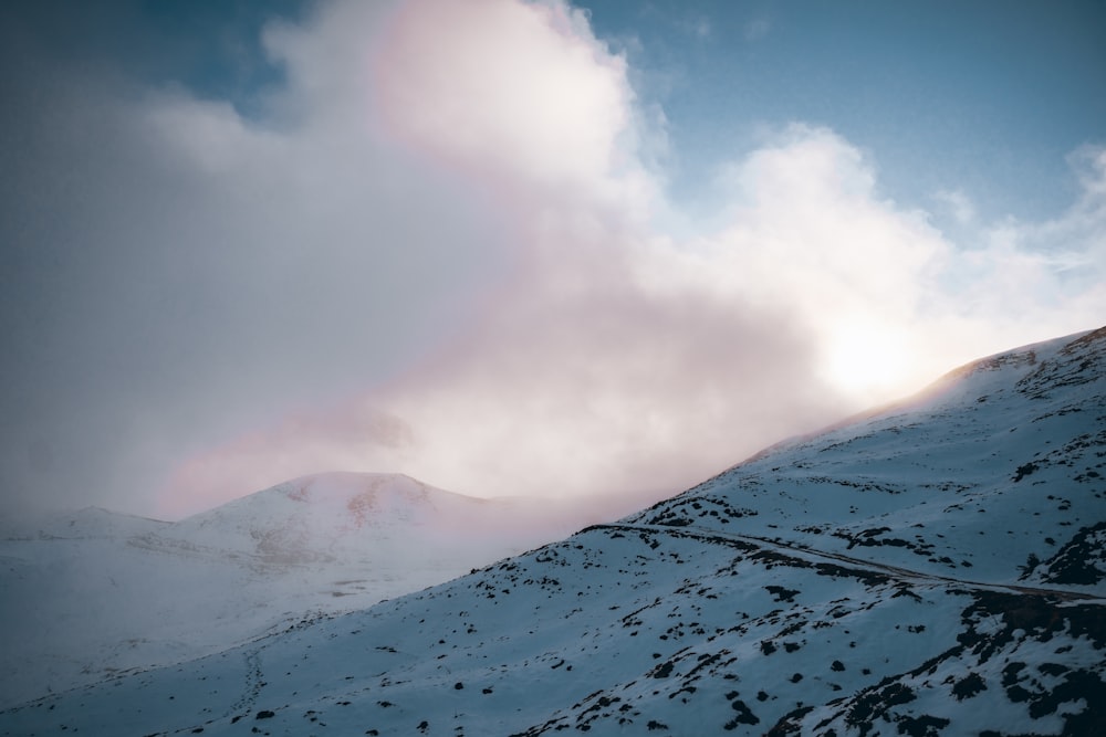 a snow covered mountain with clouds in the sky