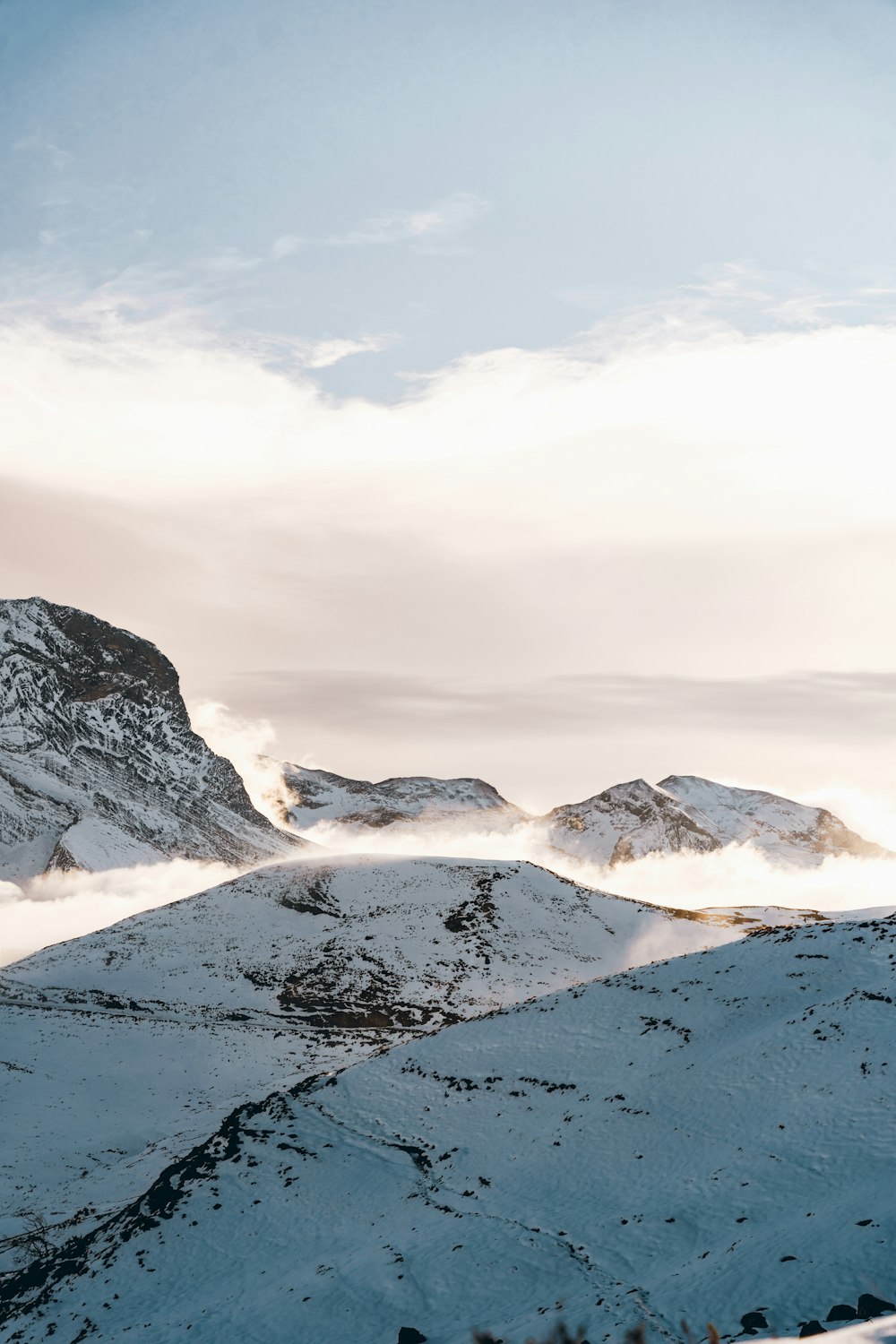 a snow covered mountain range with clouds in the sky