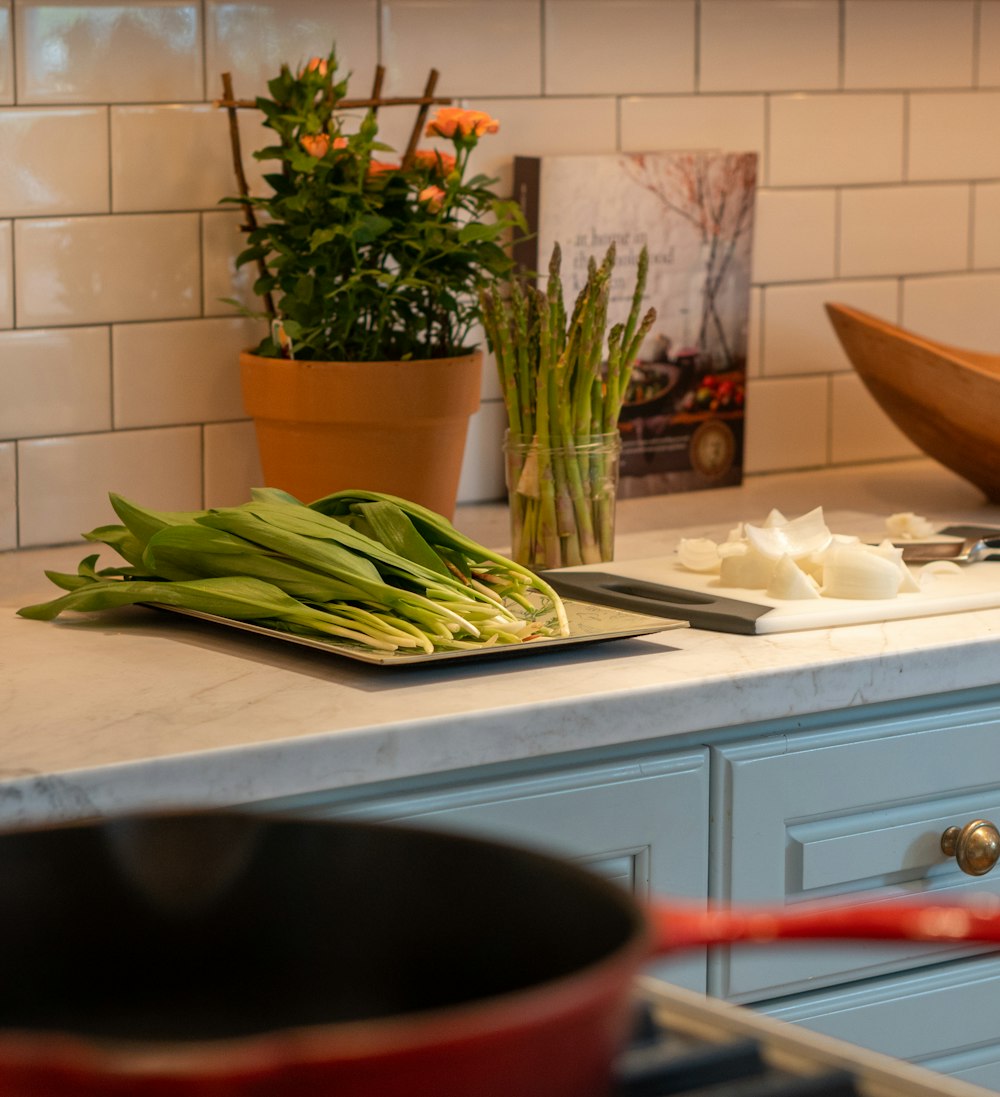 a kitchen counter with a potted plant and a cutting board