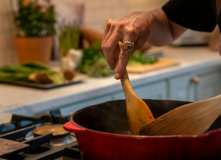 A hand stirring a red pot on the stove in a home kitchen
