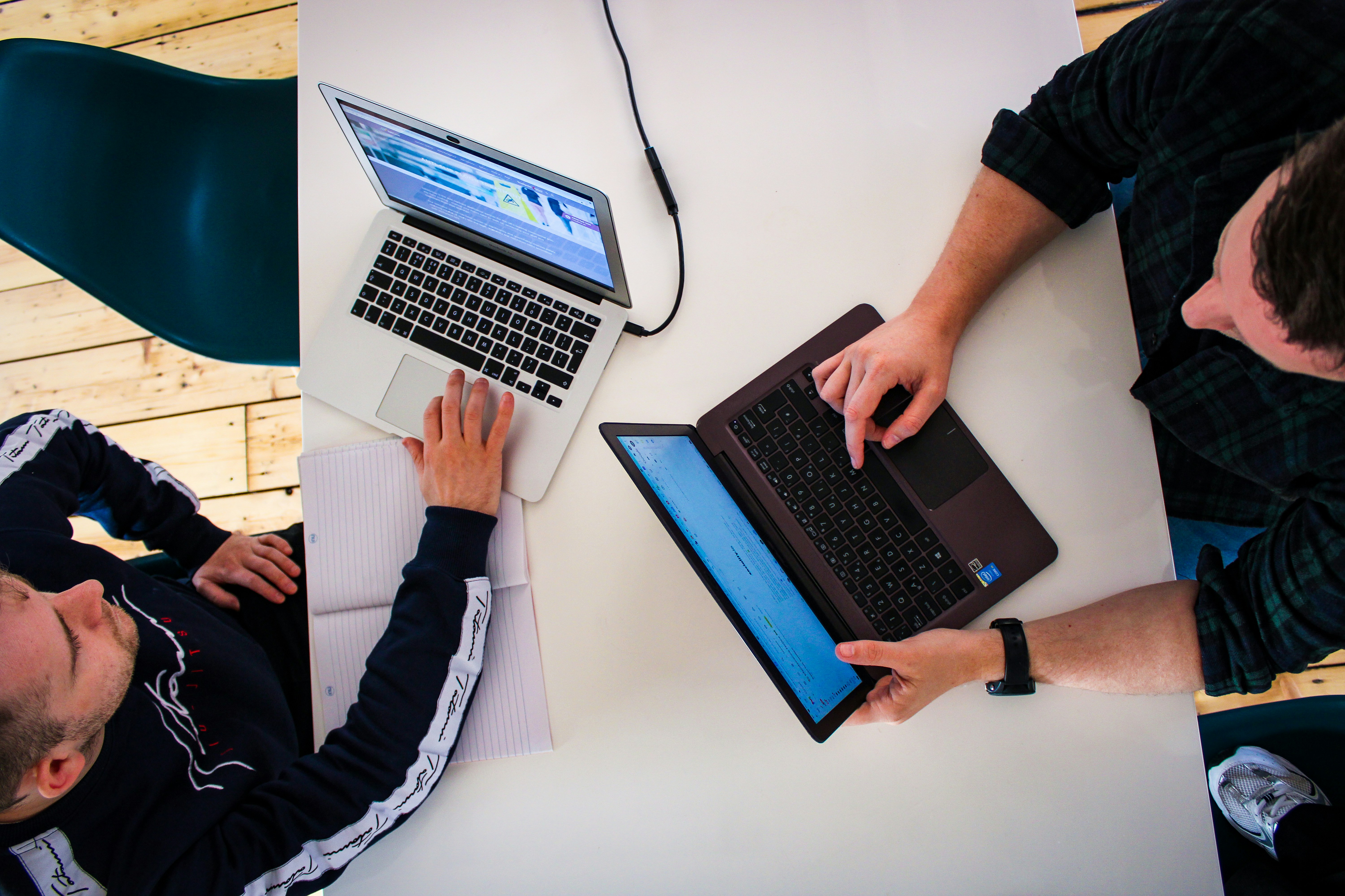 Digital marketing team in office working and reviewing client work on laptops on white board room table and wooden floors