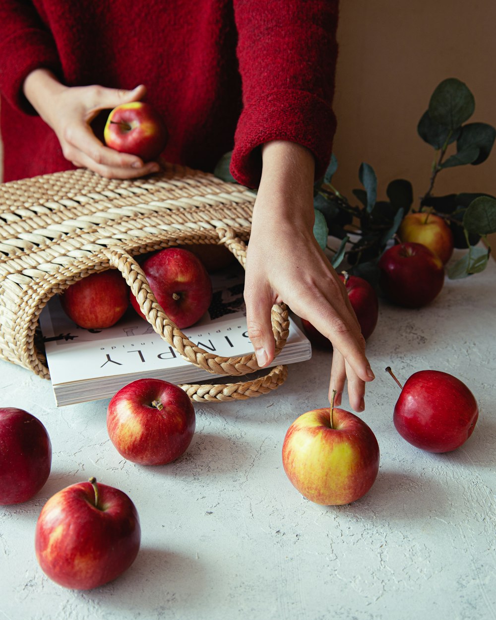 a person picking apples from a basket on a table