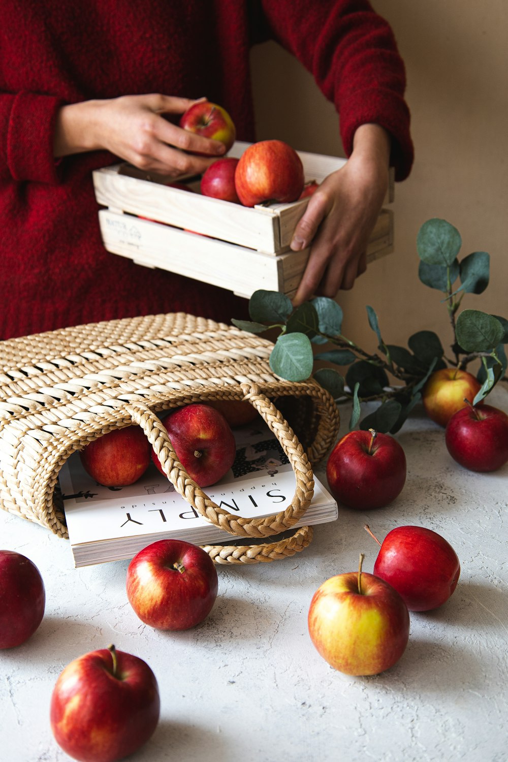 a woman holding a box of apples on top of a table