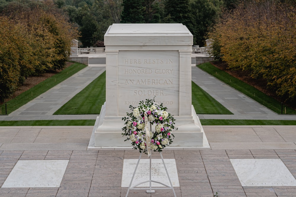 um memorial com uma coroa de flores e flores na frente dele