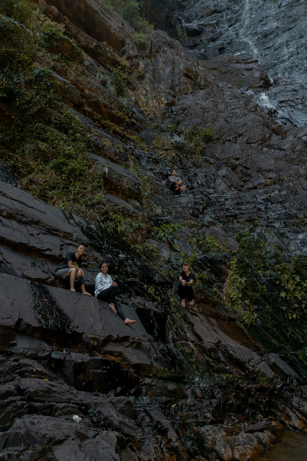un groupe de personnes assises sur un rocher à côté d’un plan d’eau