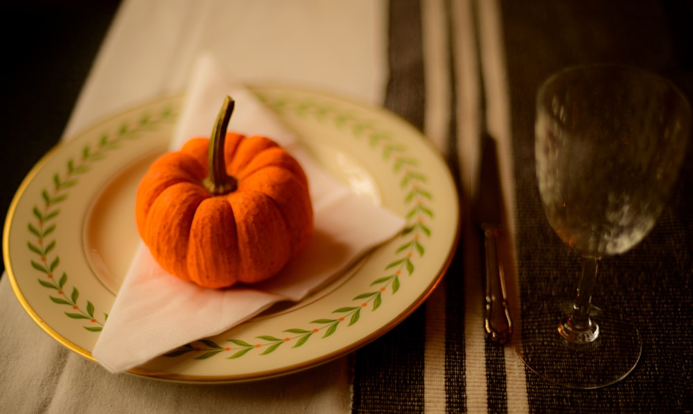 a small orange pumpkin sitting on top of a plate