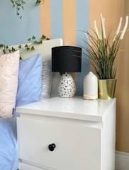 Close-up of a neatly arranged bedside table with a lamp and fresh flowers.