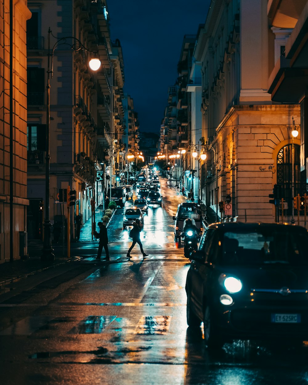 a couple of people crossing a street at night