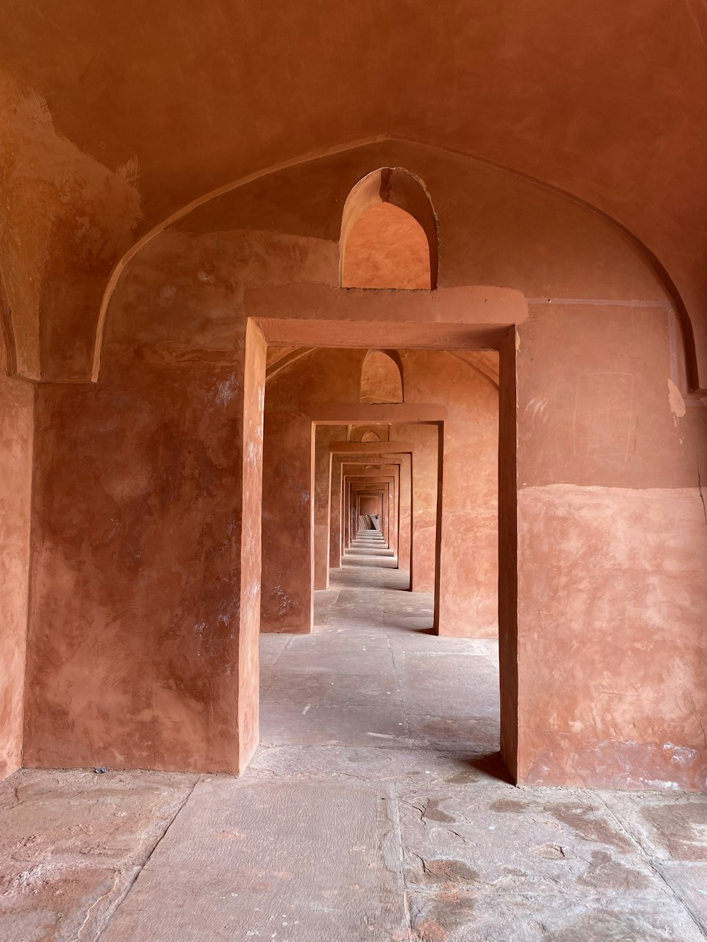 un long couloir avec des arches et une horloge sur le mur