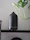 A sleek, minimalist diffuser glowing softly on a bedside table surrounded by plants.