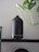 A collection of essential oil diffusers placed on a wooden shelf surrounded by green plants.