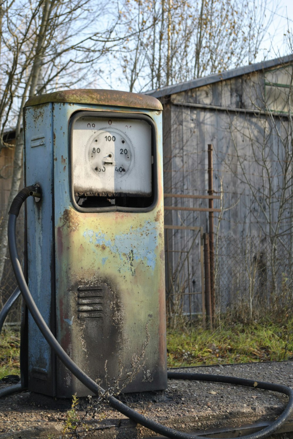 an old rusty gas pump sitting on the side of a road